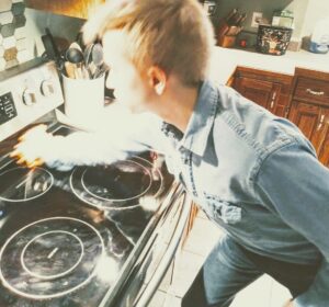 A cleaner meticulously cleaning a kitchen stovetop by RJ Cleaning Services in Richmond, KY