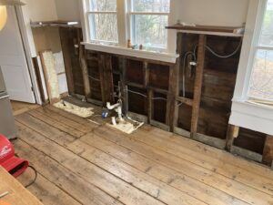 A kitchen undergoing water damage demolition with walls removed and plumbing exposed by CleanBright Surface Restoration in Latham, NY.