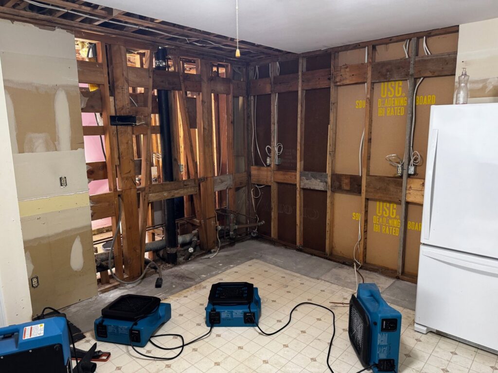 A kitchen undergoing water damage restoration with drying equipment and exposed studs by RestoPros in Bangor, ME.