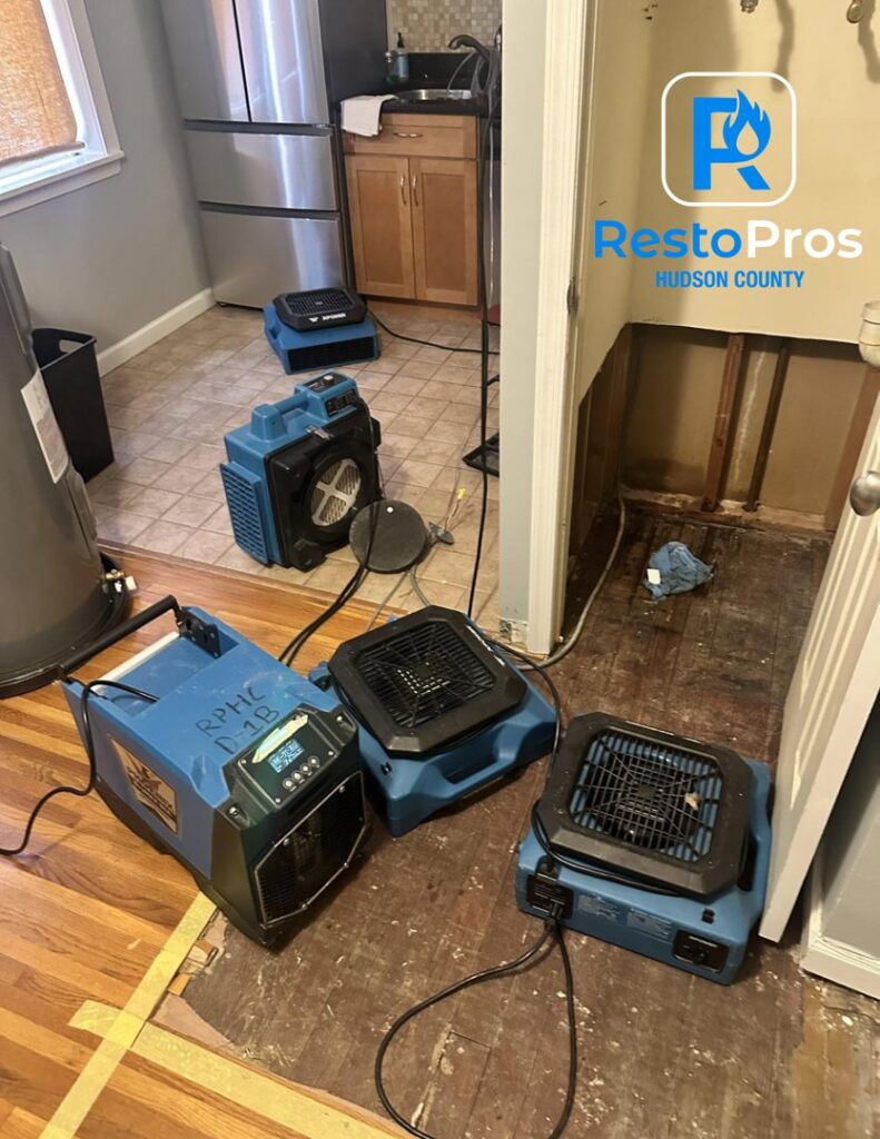 Water damage drying equipment in a kitchen with a removed wall section by RestoPros Hudson County in Jersey City, NJ.