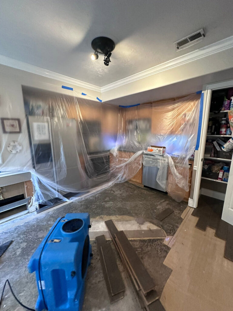 A kitchen undergoing water damage restoration with plastic containment and drying equipment by Utah Flood Guys in Sandy, UT.