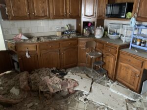 A kitchen with significant water damage and debris from a ceiling leak, undergoing restoration by Orion Construction in North Canton, OH.