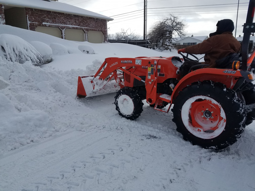 A Kubota tractor with a front-end loader performing snow removal for R & S Hauling and Landscape, LLC in Yakima, WA.