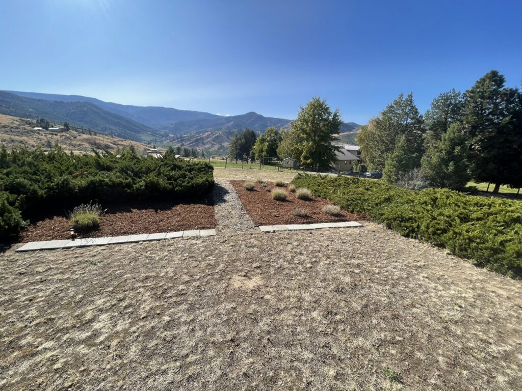 A beautifully landscaped area with mulch and plants, offering a scenic mountain view, maintained by Jerman Lawn Care in Bozeman, MT.