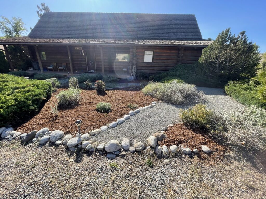 A beautifully landscaped front yard featuring mulch, decorative rocks, and well-maintained shrubs by Jerman Lawn Care in Bozeman, MT.