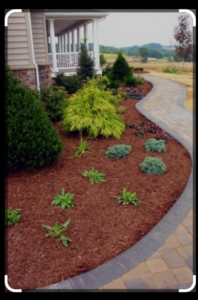 A professionally landscaped garden bed with mulch and a paved pathway by Amazing Lawns & Lighting in Omaha, NE.