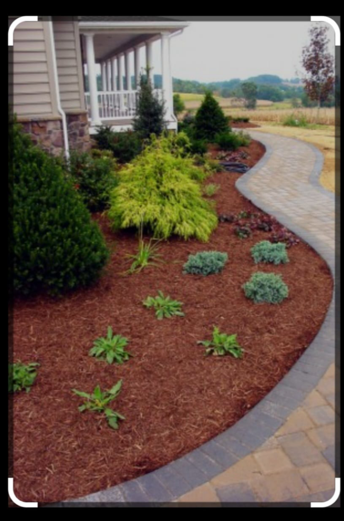 A professionally landscaped garden bed with mulch and a paved pathway by Amazing Lawns & Lighting in Omaha, NE.