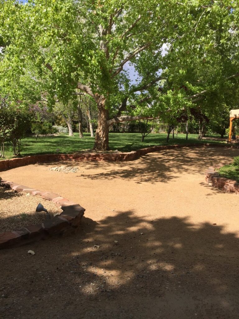 A well-maintained landscaped path leading to a lush grassy area with trees by Green Thumb Lawn Care & Maintenance, LLC in Rio Rancho, NM.
