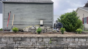 Landscaping tools next to a prepared garden bed with new plants by Steele Lawns in Portland, ME.
