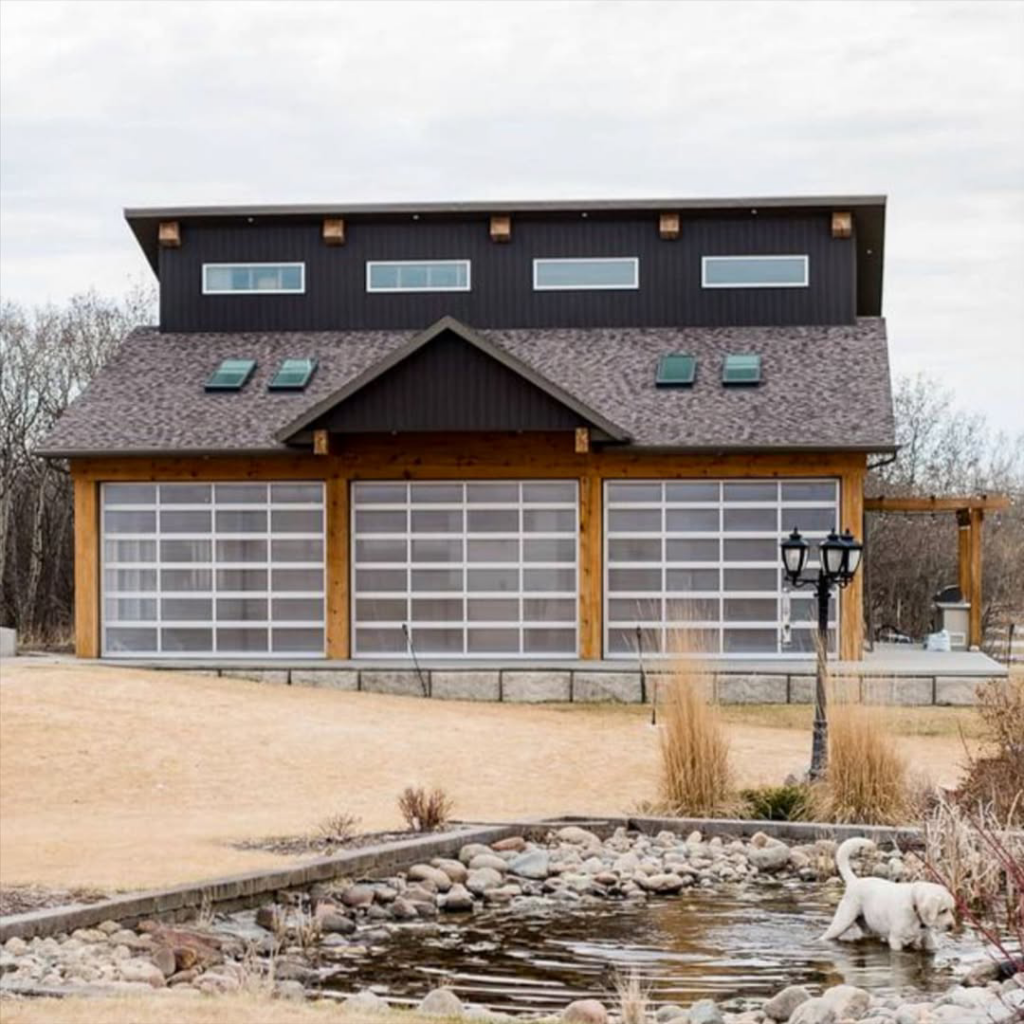 A large building showcasing three modern full-view glass garage doors installed by Bailey Garage Doors MT in Belgrade, MT.