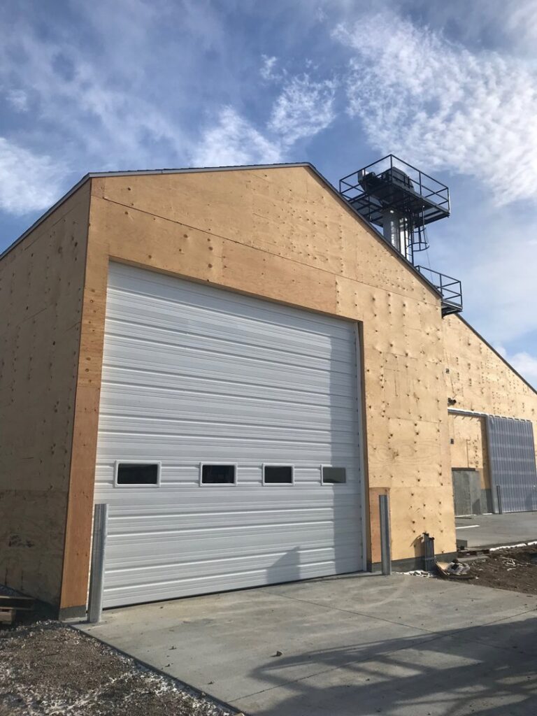 Large white commercial garage door installed on a new construction building by Elite Door in Winchester, CA.