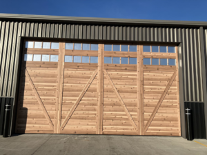 A large custom wooden garage door with many small windows installed on a commercial building by Devildog Dock N Door in Helena, MT.