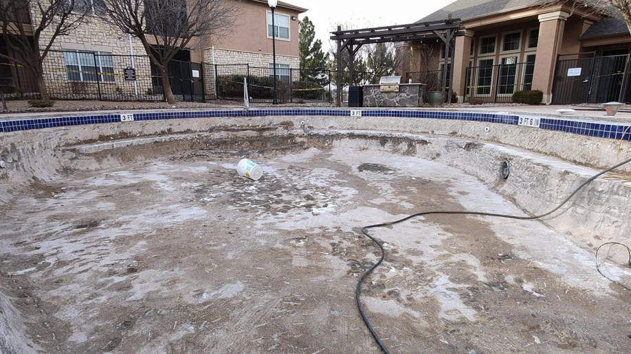 A large empty pool undergoing renovation, showing the prepared interior surface and surrounding area by J.R. Pools in Lubbock, TX.