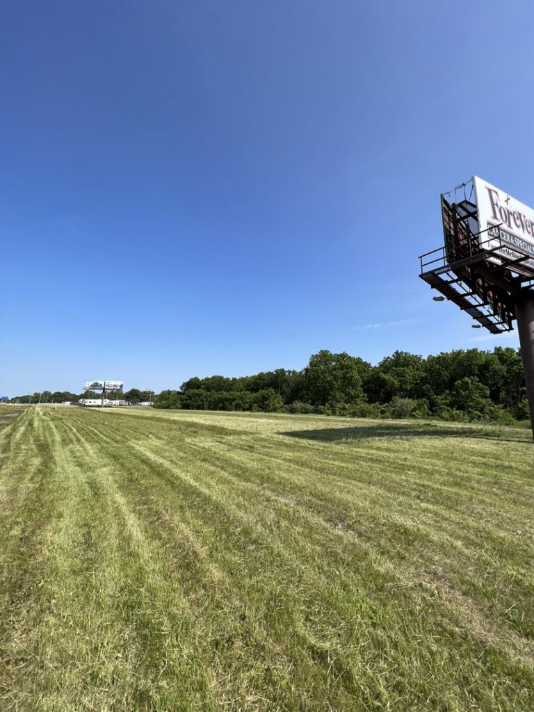 A large field of freshly mowed grass with clean stripes, showcasing professional mowing by Thompson Acres in Davenport, IA.