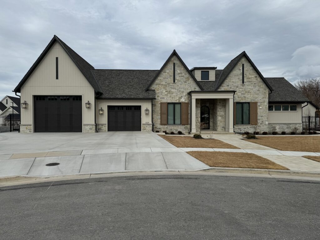 A large, elegant house featuring light gray board and batten siding and stone accents by New Look Siding in Midvale, UT.