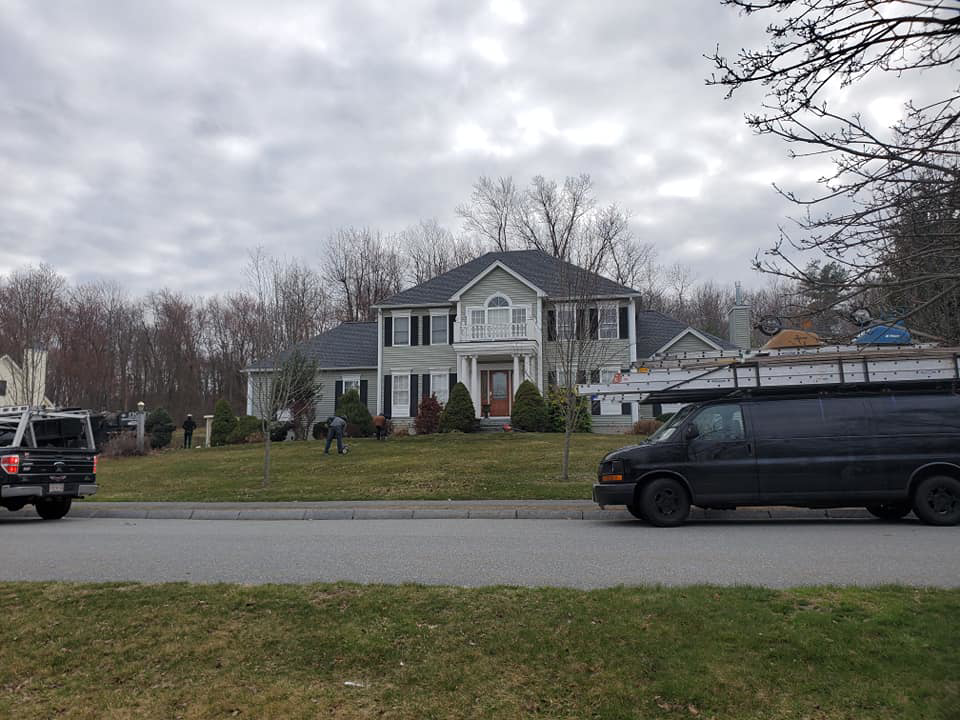 A large residential house with newly installed light green siding by Trabajo en roofing y siding in Lowell, MA.