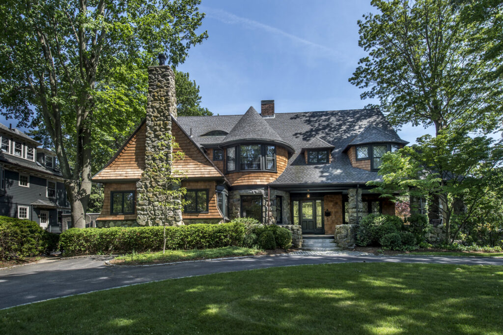 A large, elegant house featuring a combination of stone and wood shake siding, a project by United Home Experts in Ashland, MA