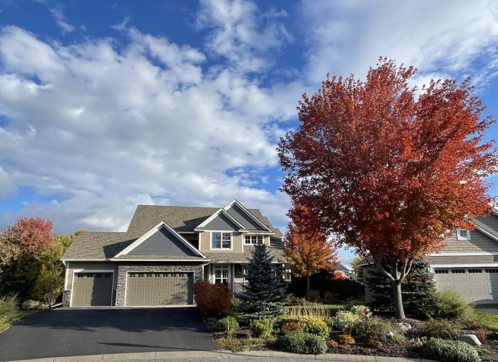 A large house with newly installed tan siding and stone accents by Storm Group Roofing in Brooklyn Park, MN.