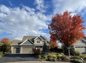 A large house with newly installed tan siding and stone accents by Storm Group Roofing in Brooklyn Park, MN.