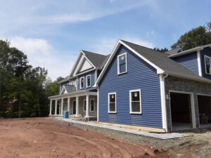 A large new construction home featuring blue horizontal siding and stone veneer by DL Roofing and Siding in New Haven, CT