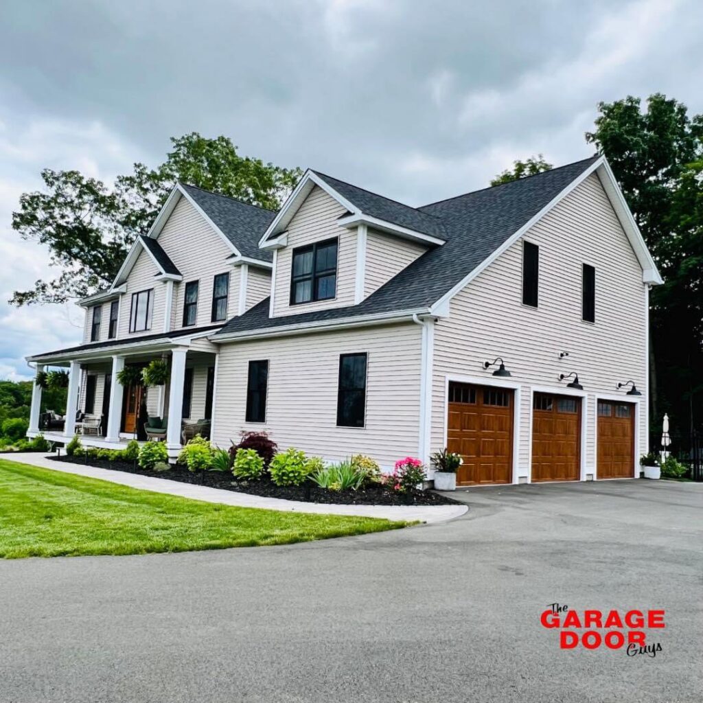 A large house featuring two newly installed wooden-look garage doors by The Garage Door Guys, LLC in New Haven, CT.