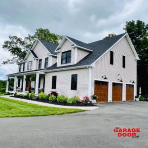 A large house featuring two newly installed wooden-look garage doors by The Garage Door Guys, LLC in New Haven, CT.