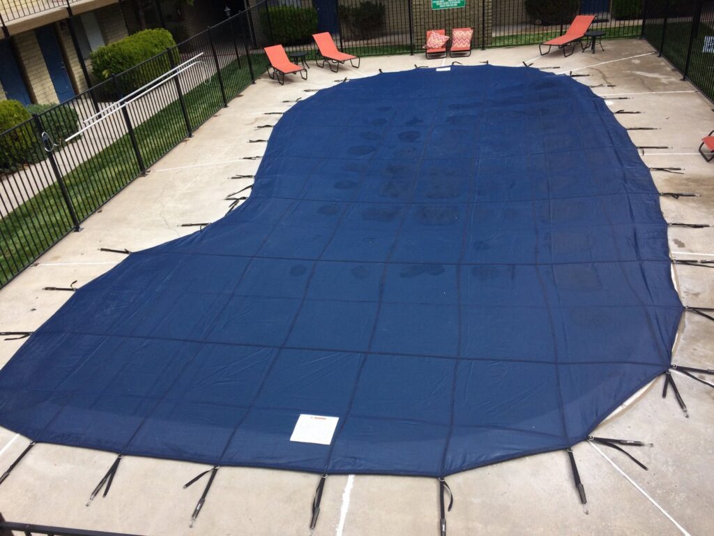 A large, irregularly shaped swimming pool with a blue safety cover, maintained by Battle Born Pool & Spa in Sparks, NV.