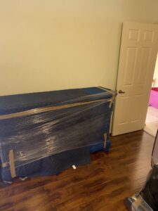 A large piece of furniture wrapped in blue moving blankets and plastic, ready for transport by Moving Marvels in Tucson, AZ.