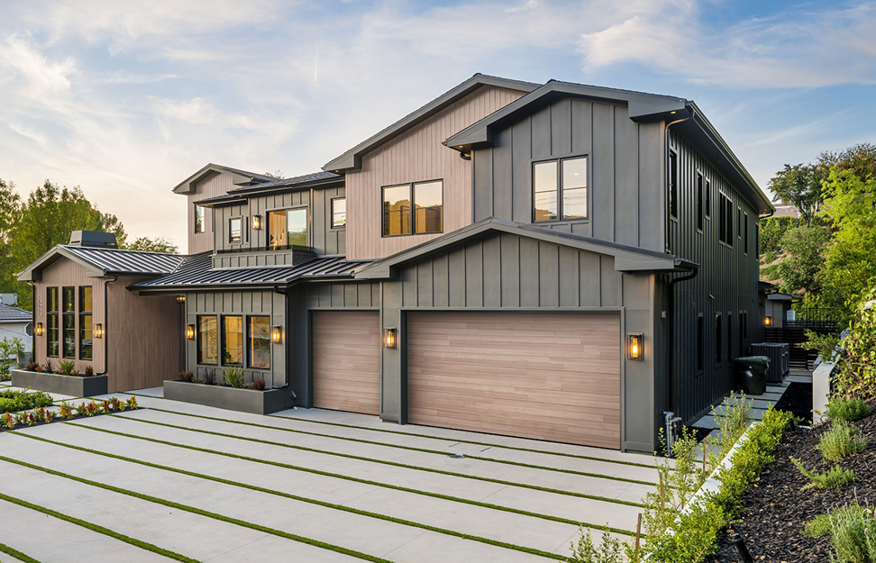 A large modern house showcasing two stylish wood-look garage doors from Standard Door Supply in Portland, ME.