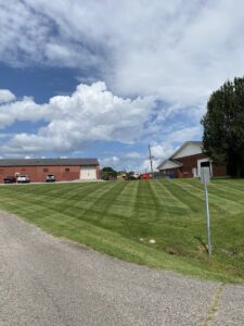 A large, perfectly mowed commercial or residential lawn with distinct stripes by The Otherside Lawn Solutions in Ankeny, IA.