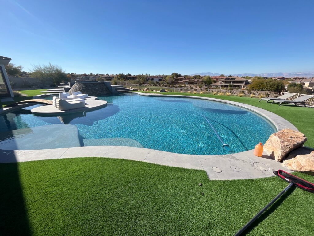 A large, clean swimming pool with a pool vacuum hose and skimmer net, showing professional cleaning by Priority Pools LV in Las Vegas, NV