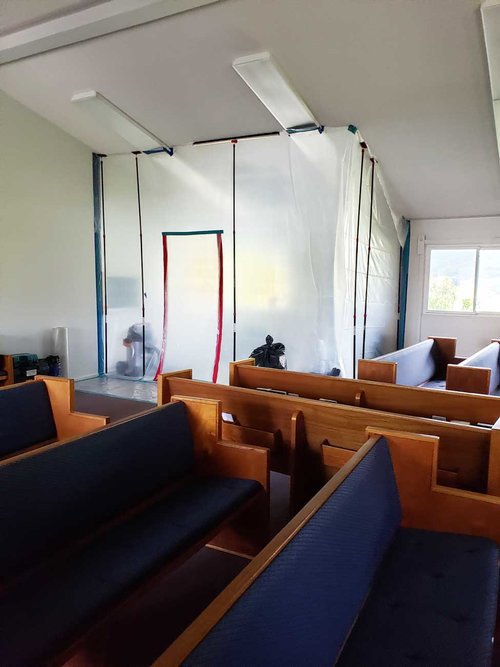 A large room with plastic sheeting set up for containment during a restoration project by Island Restoration LLC in Kapolei, HI.