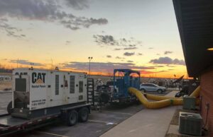 Large-scale water damage drying operation with a generator and yellow ducts leading into a building by Express Restoration in Edmond, OK.