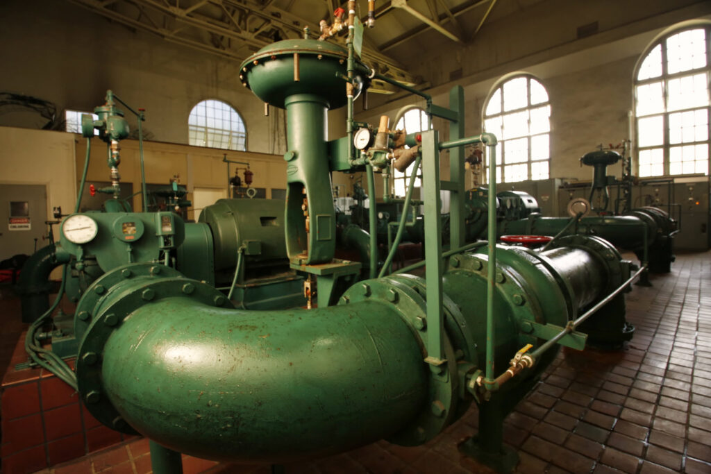 Large green water pipes and industrial machinery inside a pump station managed by Honolulu Board of Water Supply in Honolulu, HI.