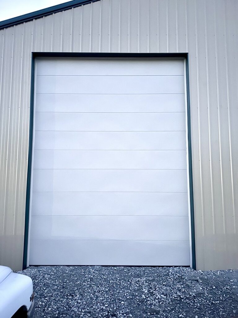 A large white commercial garage door installed on a metal building by LaFrancis Overhead Door LLC in Little Rock, AR