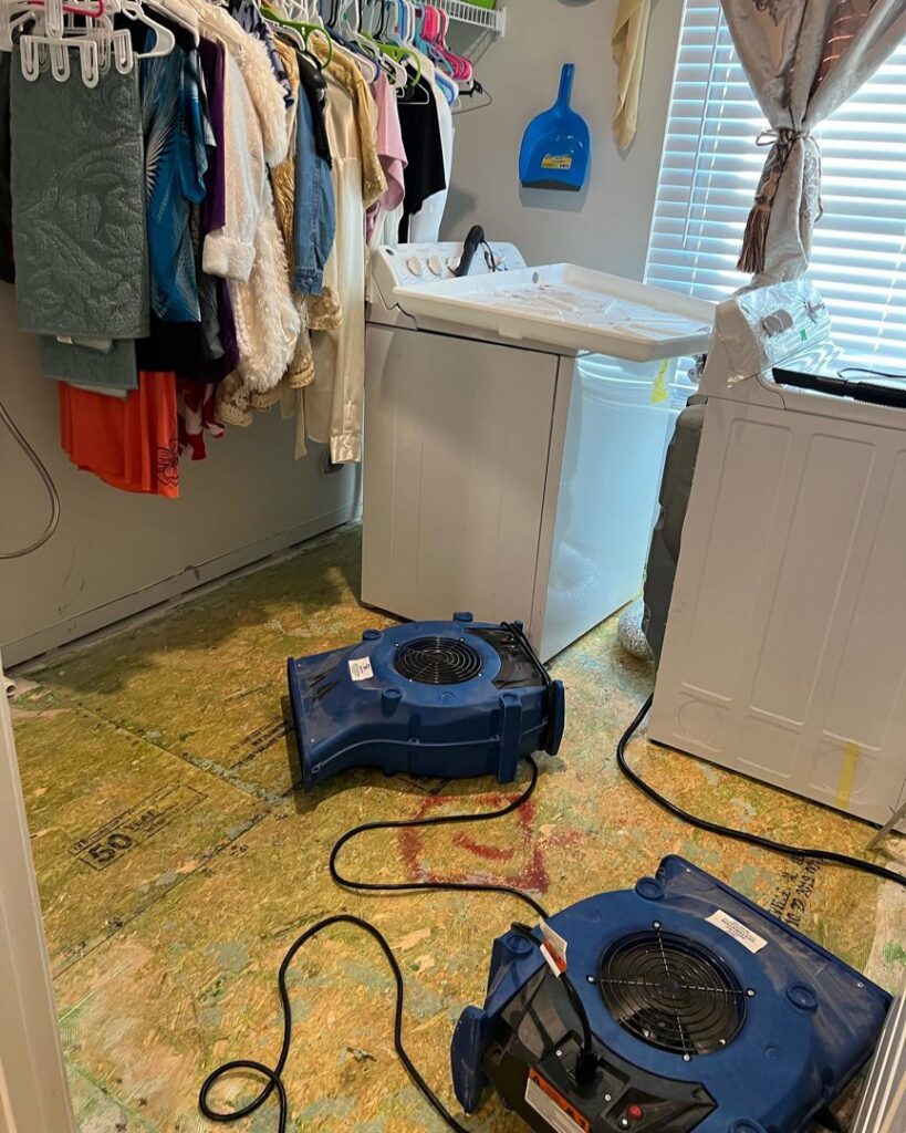 Air movers drying the subfloor in a laundry room after water damage restoration by Sentry Restoration in Volo, IL