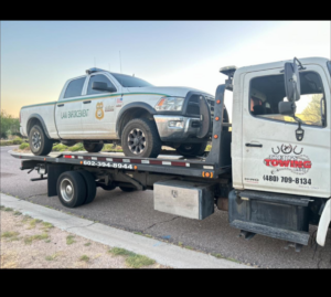 A law enforcement pickup truck being transported on a flatbed tow truck by Trejo's Towing LLC in Phoenix, AZ.