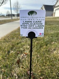 A lawn care application sign placed in a residential lawn by Ankeny Grass Guys in Ankeny, IA, advising to stay off for 24 hours.