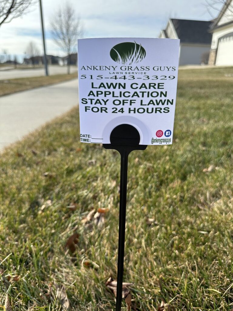 A lawn care application sign placed in a residential lawn by Ankeny Grass Guys in Ankeny, IA, advising to stay off for 24 hours.