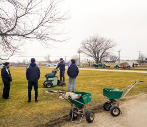 A team of lawn care professionals with spreaders and equipment from Tee Time Lawn Care Davenport, IA.