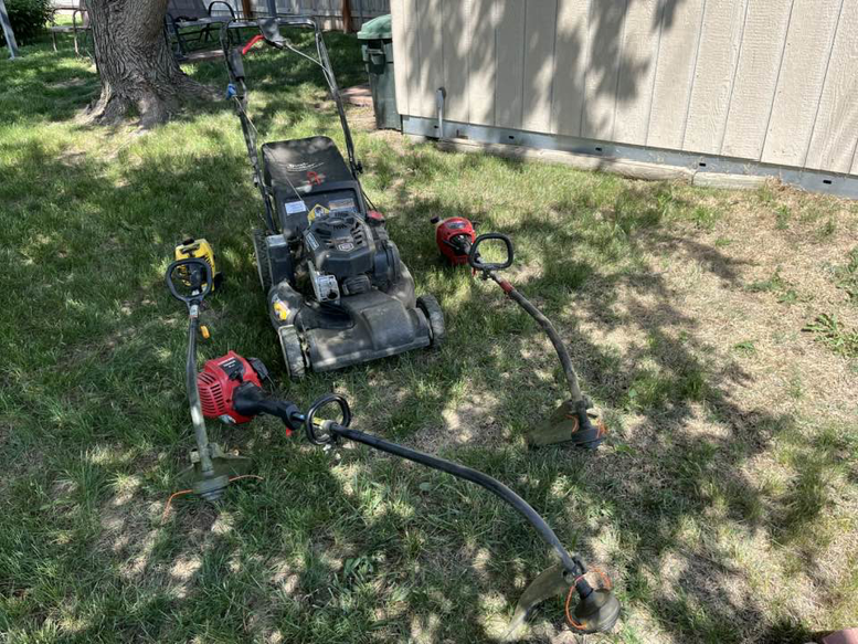 Lawn care equipment including a mower and string trimmers on grass for Bucks Lawn Care LLC in Lincoln, NE.