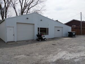 Professional lawn care equipment, including a spreader, parked outside the Nice & Precise Lawn Care facility in Ames, IA.