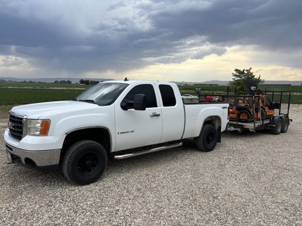 A Luna's Lawn Care LLC truck towing a trailer with a riding mower, transporting equipment in West Des Moines, IA.