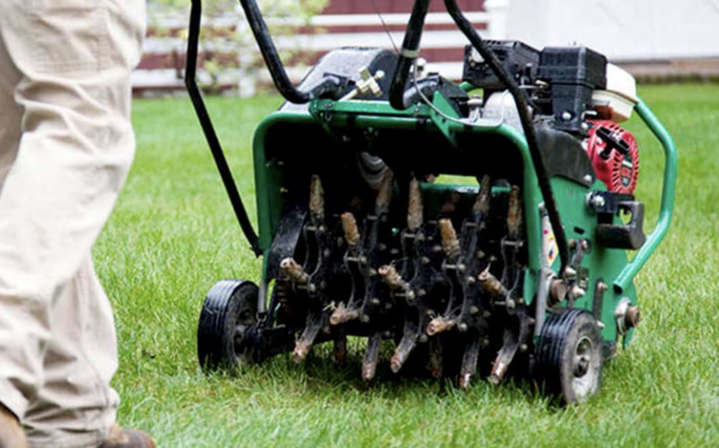 A lawn care professional operating a core aerator on a green lawn for Heath's Lawn Care in Omaha, NE.