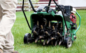 A lawn care professional operating a core aerator on a green lawn for Heath's Lawn Care in Omaha, NE.