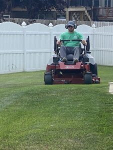 A lawn care professional operating a zero-turn riding mower to cut grass for Heath's Lawn Care in Omaha, NE.
