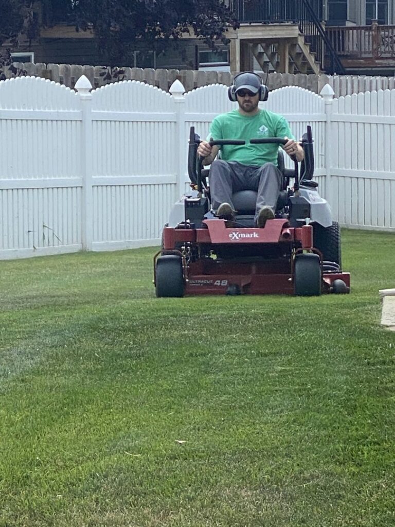 A lawn care professional operating a zero-turn riding mower to cut grass for Heath's Lawn Care in Omaha, NE.