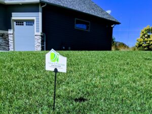 A Nice & Precise Lawn Care sign proudly displayed on a lush, green residential lawn in Ames, IA, indicating professional service.