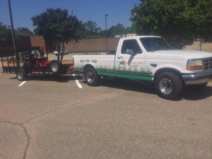 A white pickup truck with Turner Lawn Care branding towing a zero-turn mower in Tupelo, MS.