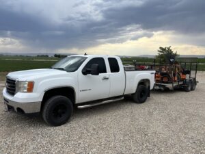 A Luna's Lawn Care LLC truck towing a trailer with a mower, transporting equipment for a job in West Des Moines, IA.